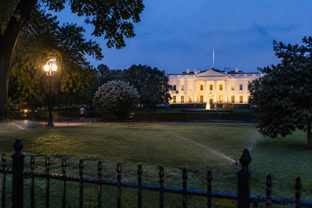 A floodlit government building facade glowing white against a deep blue evening sky