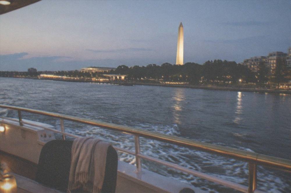 The Washington Monument and memorials lit up at night seen from the water