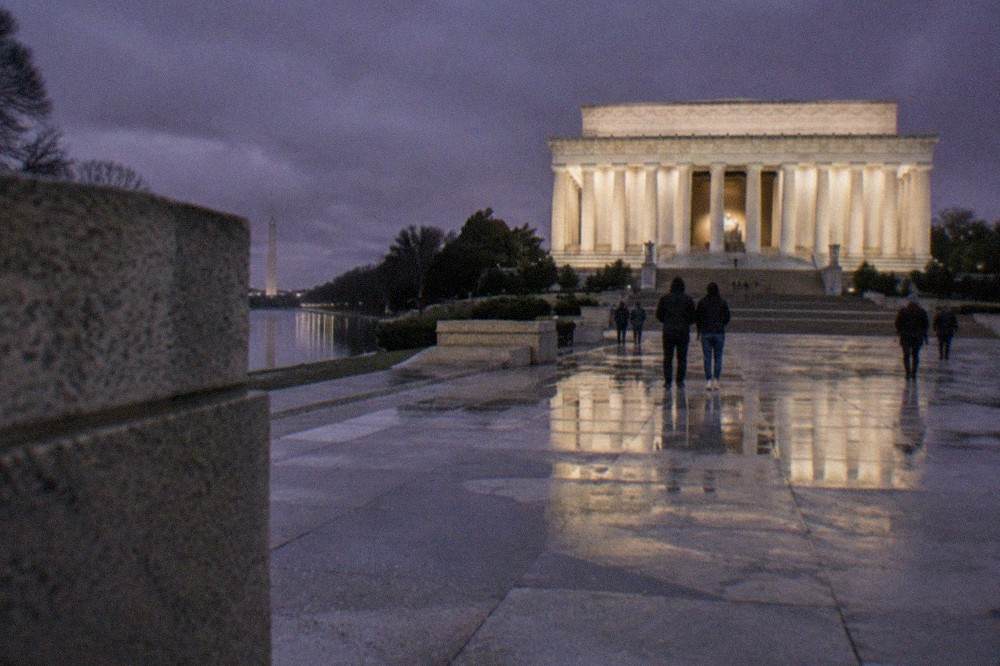 The Lincoln Memorial glowing white against a dark sky, with its columns lit from below