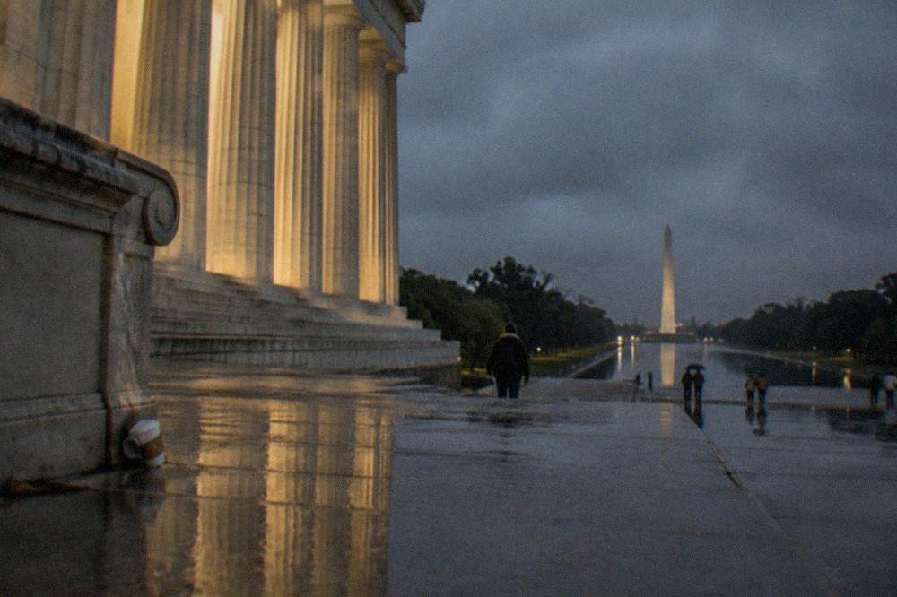 The Lincoln Memorial illuminated at night with the Reflecting Pool stretching toward the Washington Monument