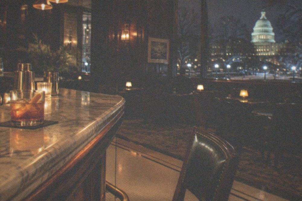 A warmly lit historic hotel bar interior with dark wood and brass fittings