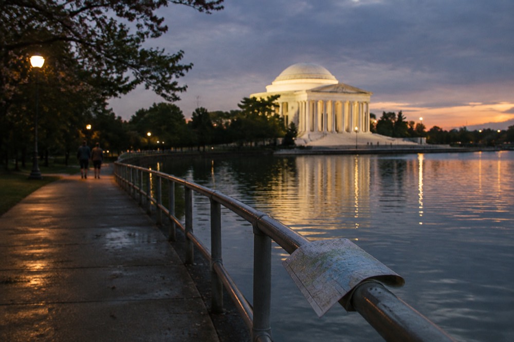 Lit paved walkway curving past the illuminated Jefferson Memorial at night