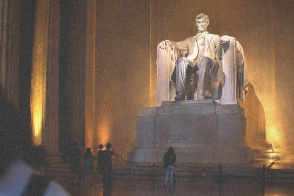 The Lincoln Memorial chamber at night with the seated statue lit and the Gettysburg Address inscription visible on the wall