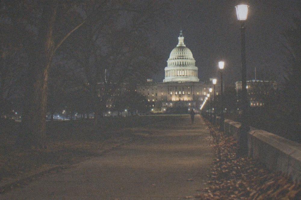 An empty lit walkway stretching toward the floodlit Capitol dome at night