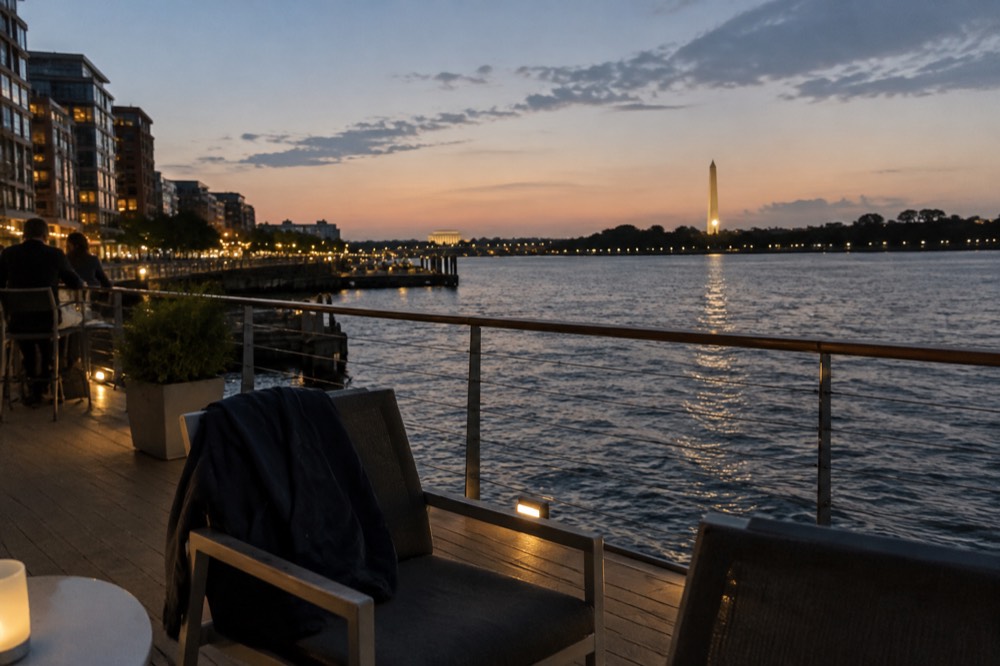 The Washington Monument and memorials lit up at night as seen across the dark river water