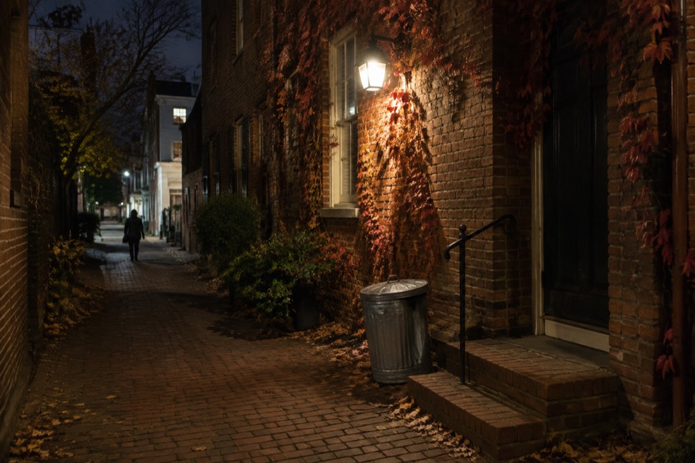 A dark alley in Georgetown at night with brick walls lit by a single lamp