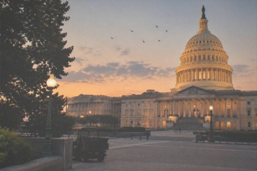 Warm floodlights washing over stone columns of a memorial on the National Mall after dark