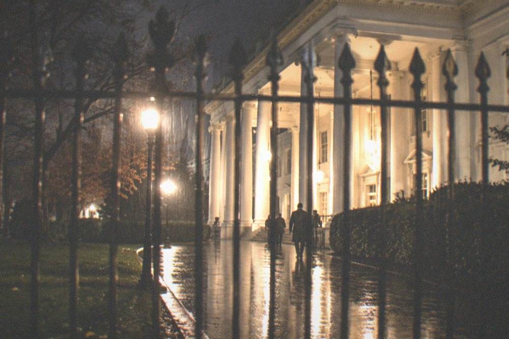 A wide empty walkway on the National Mall lit by memorial lights under a dark sky