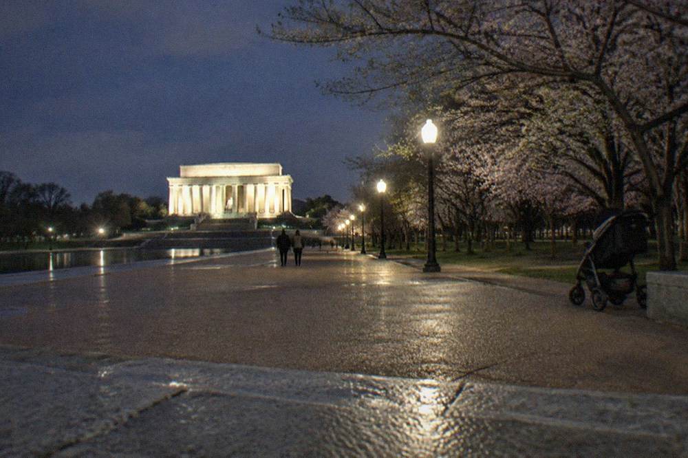 Wide lit walkway near the Lincoln Memorial at night with empty paths and soft lighting