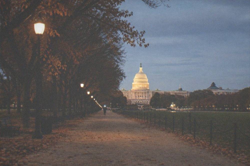 Evening view along the National Mall with lit paths and memorials glowing under dark sky
