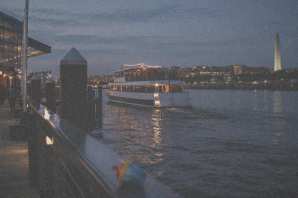 Dinner cruise boat on the Potomac River at night with city lights reflected on the water
