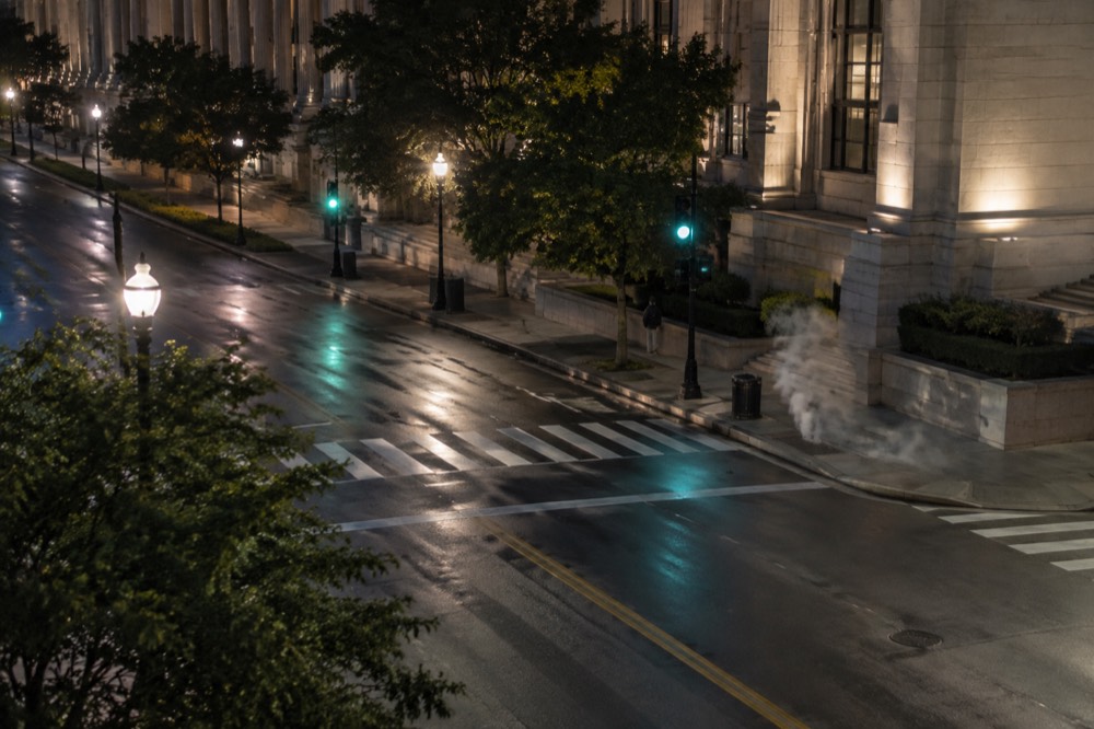 A quiet downtown Washington DC street corner with traffic lights glowing after dark