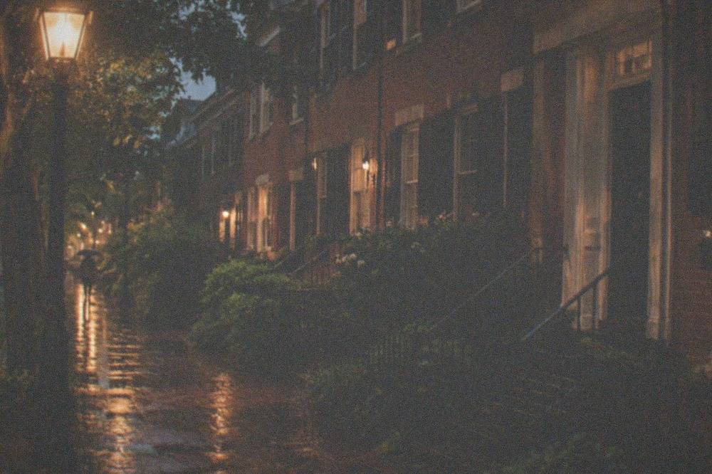 A candlelit brick street in Georgetown at night with lampposts glowing